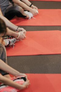 Participants stretch on red yoga mats, focusing on flexibility and wellness in a fitness class.