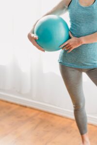 A woman holding a fitness ball during a home exercise session, highlighting healthy lifestyle.