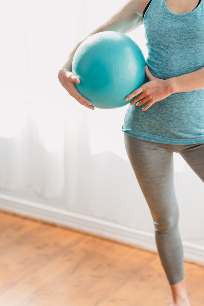 A woman holding a fitness ball during a home exercise session, highlighting healthy lifestyle.