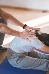 Person stretching on a yoga mat with assistance indoors. Exercise and wellness concept.
